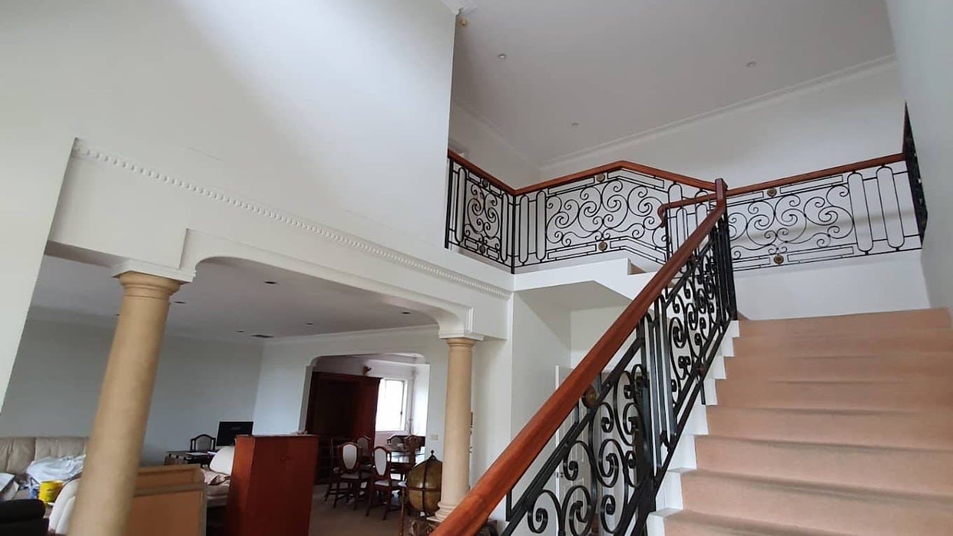 Detailed white interior painting around a staircase and decorative railing