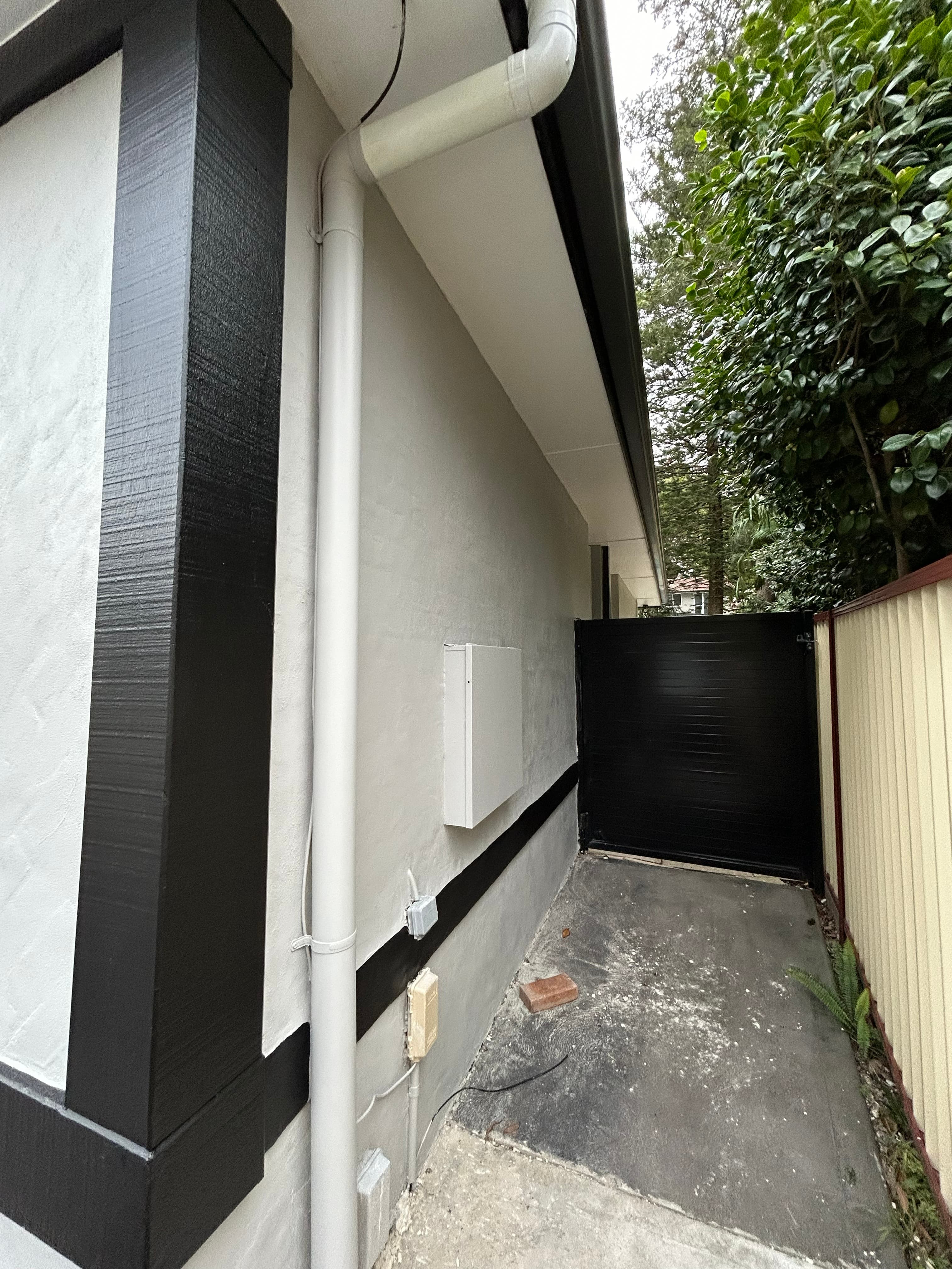 Carlingford side passage after exterior repainting with black gate and white downpipes