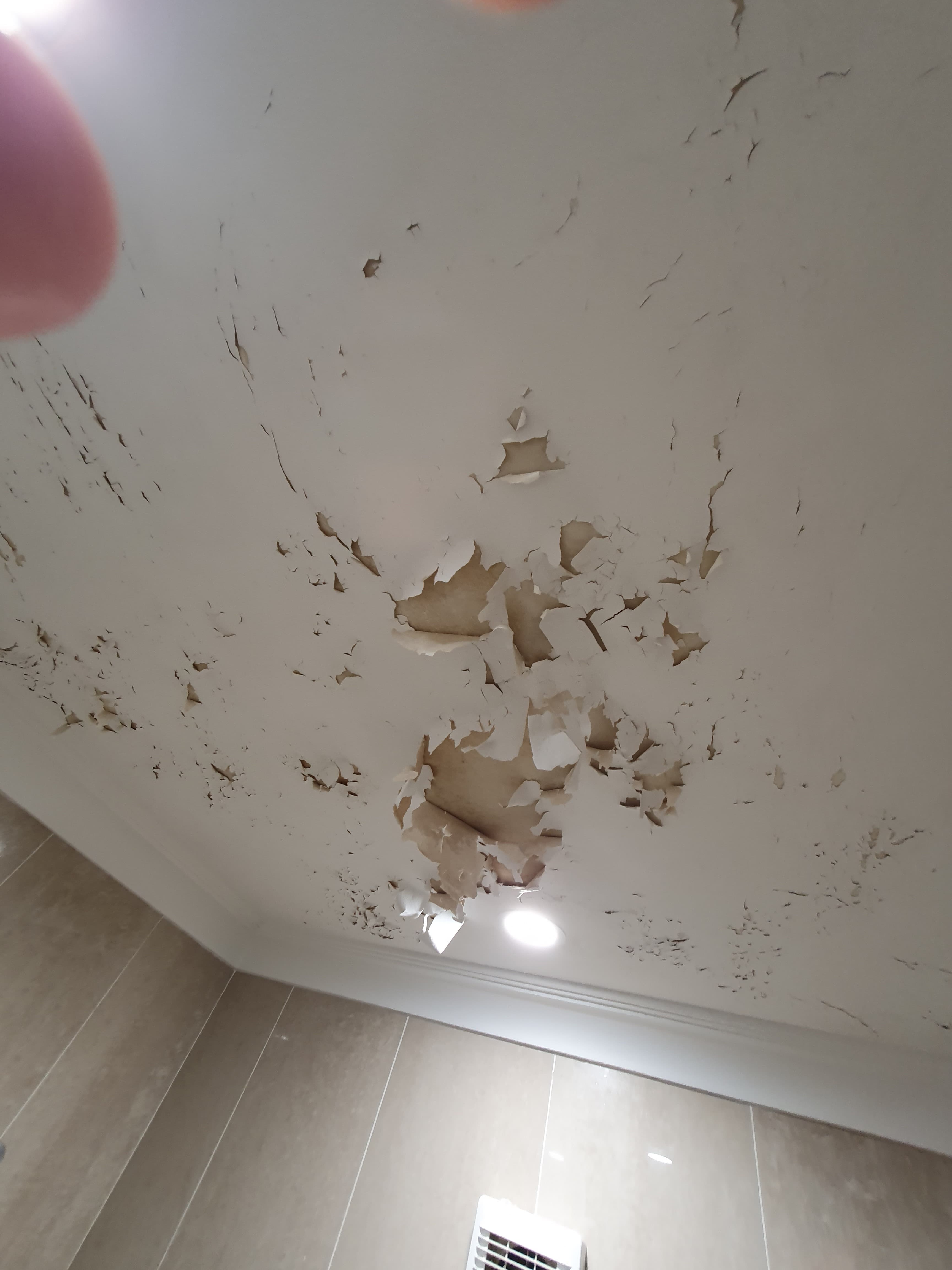 Bathroom ceiling with peeling paint and moisture damage before restoration